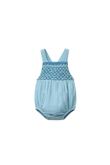 Front view of blue romper with straps and embroidered detail on the chest.