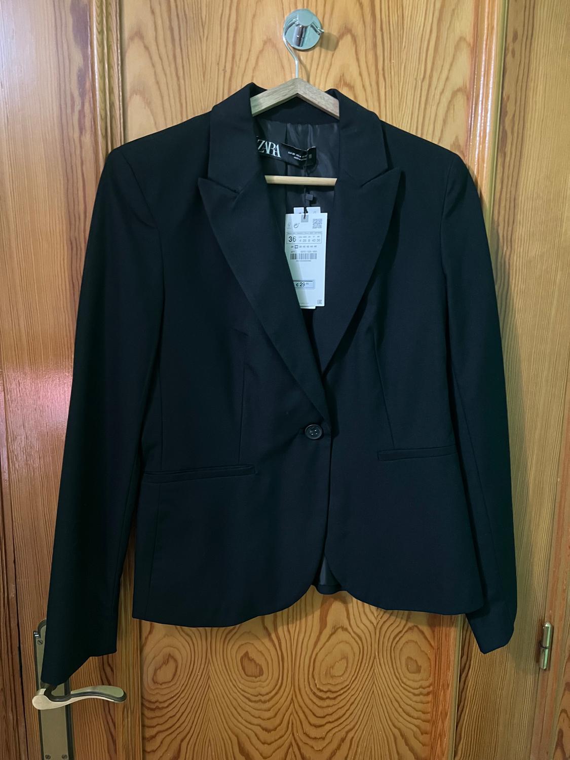 Front view of a black blazer with a classic lapel and side pockets.
