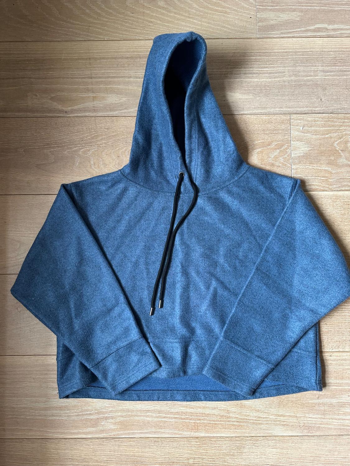 Front view of a blue hoodie with black drawstrings.