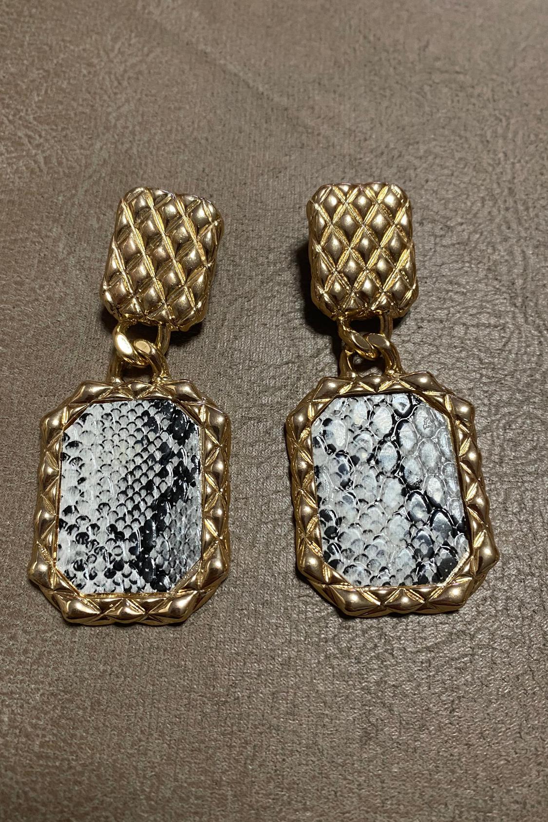 Golden earrings with a snakeskin design at the bottom.