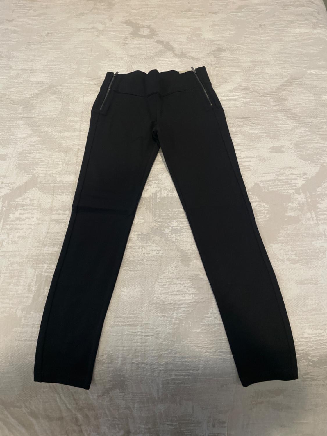 Front view of black trousers with zips on the side pockets.
