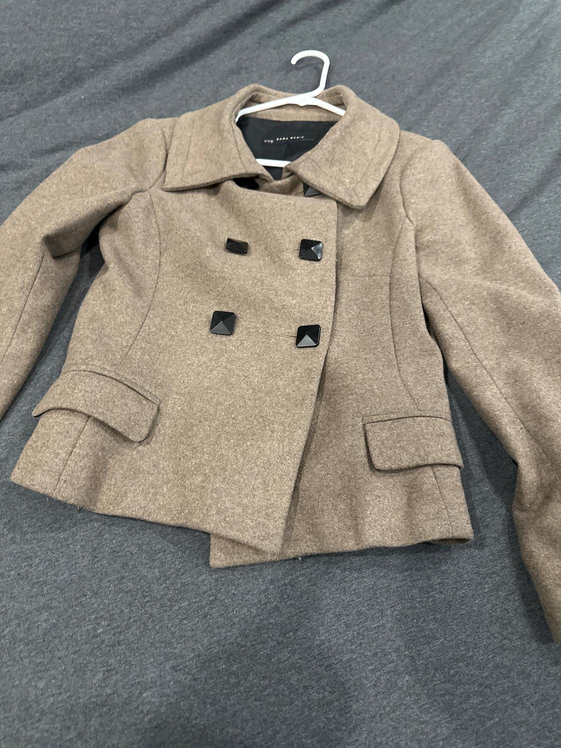 Front view of a brown jacket with square black buttons and flap front pockets.