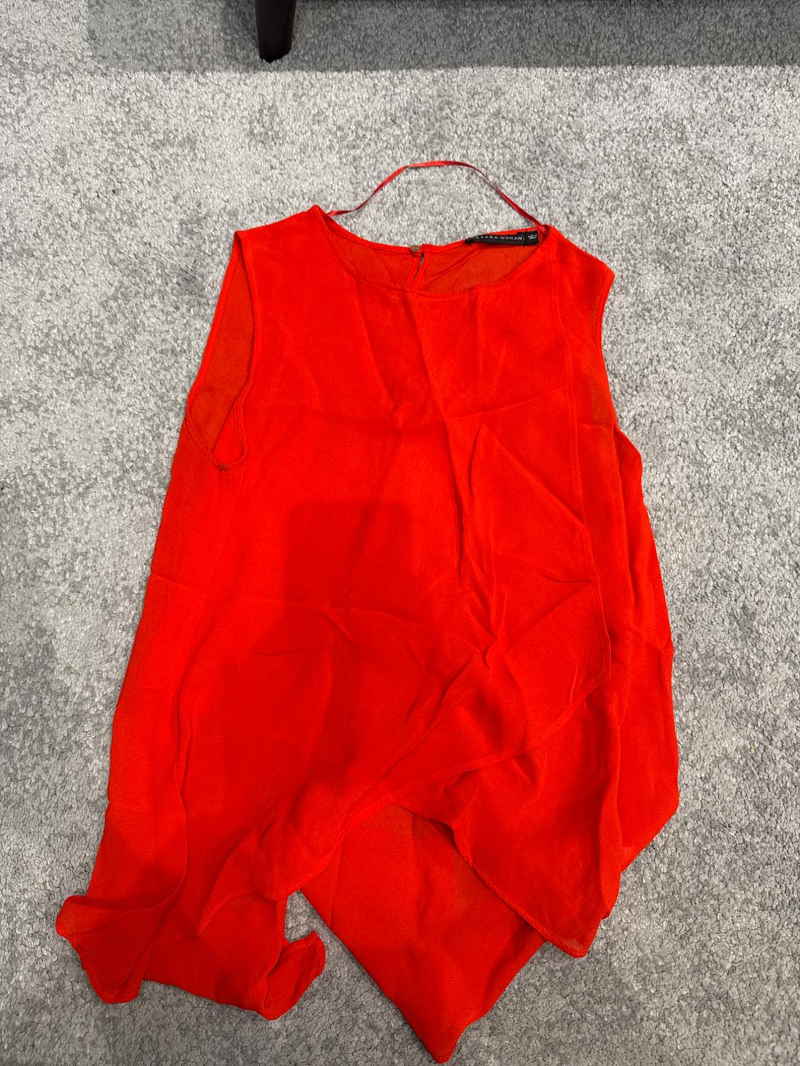 Front view of a sleeveless red dress with a round neck and an asymmetric hem.