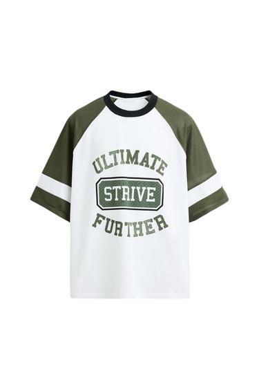 White t-shirt with green sleeves and black collar. Text on the front: "ULTIMATE STRIVE FURTHER" in green letters.