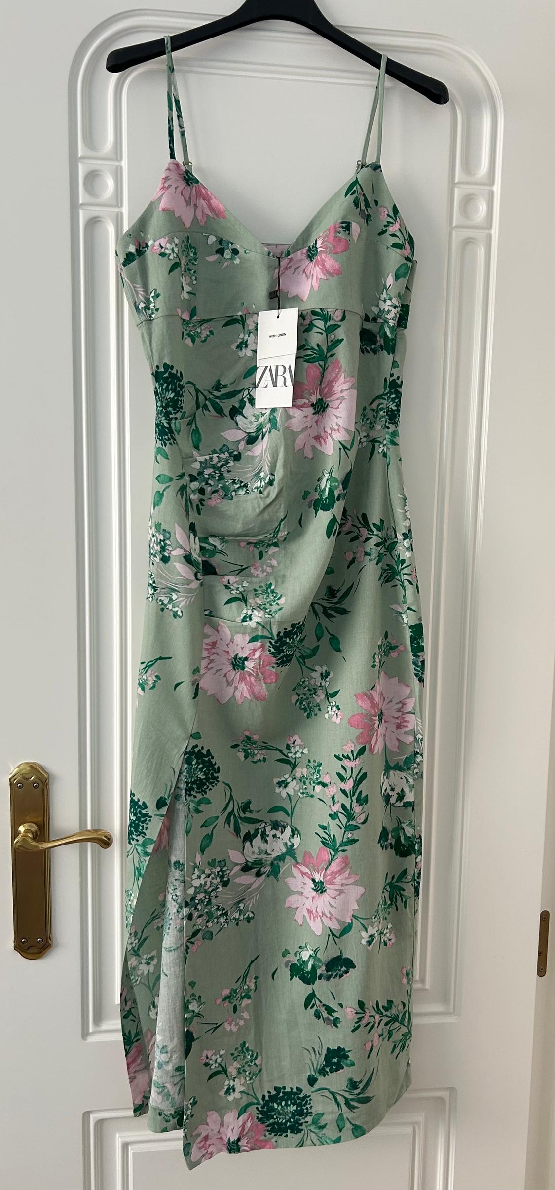 Green dress with pink and green floral print, hanging on a black hanger. Visible label with text: "WITH LINEN ZARA".