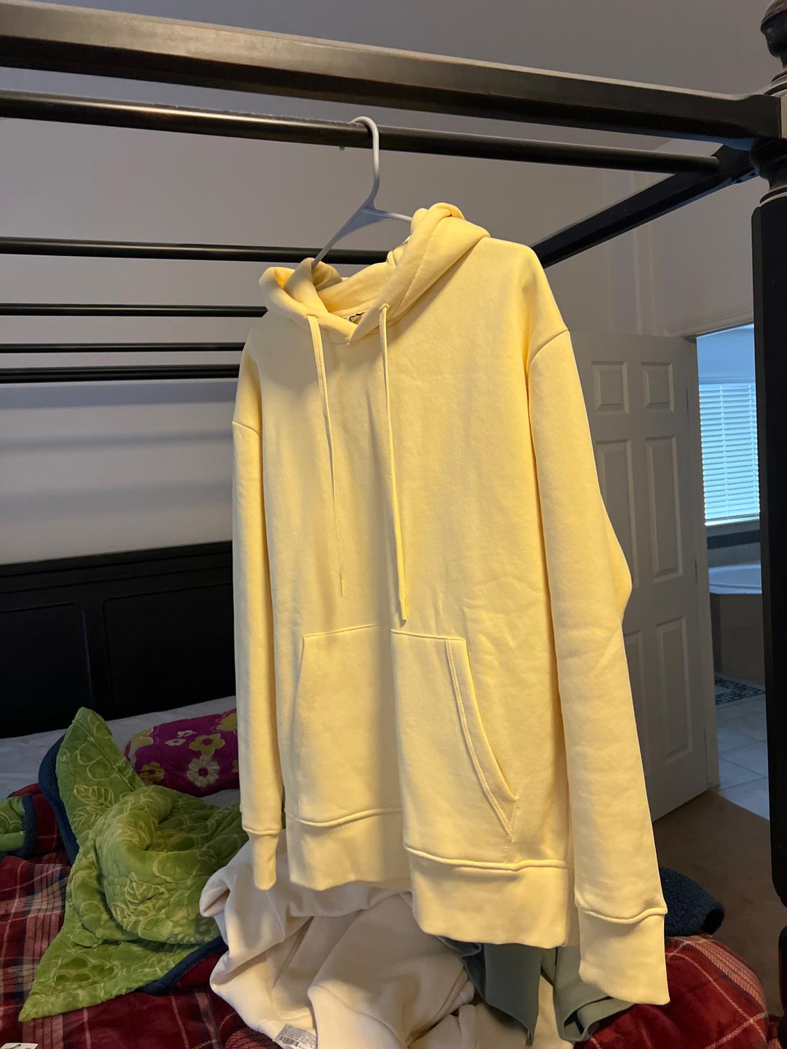 Side view of a yellow hooded sweatshirt with a front kangaroo pocket.