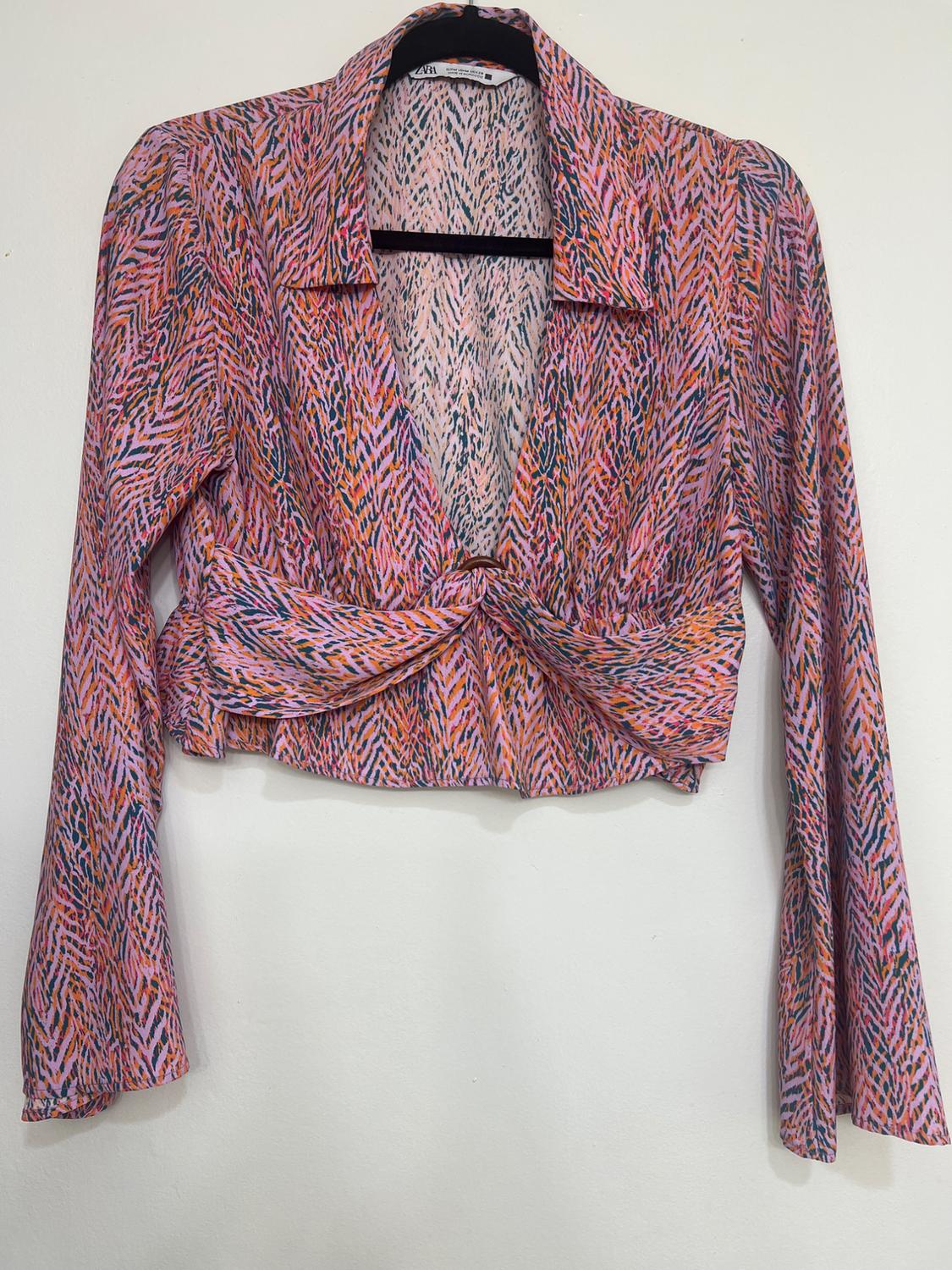 Front view of a multicoloured print blouse with a front knot and long sleeves.