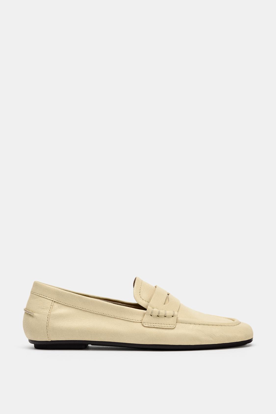 Side view of beige loafer with black sole and stitching detail on the vamp.