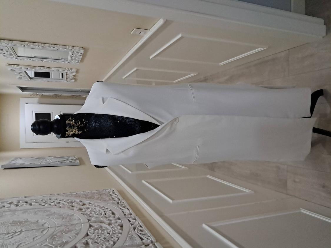 Mannequin with a long white coat against a beige wall background decorated with white mouldings and a white door.