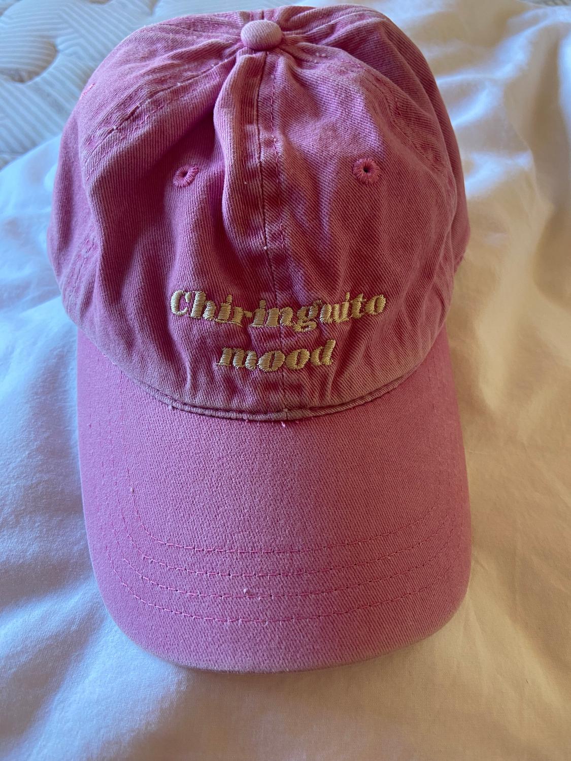 Pink cap with "Chiringuito mood" embroidered in yellow text, on a white surface.