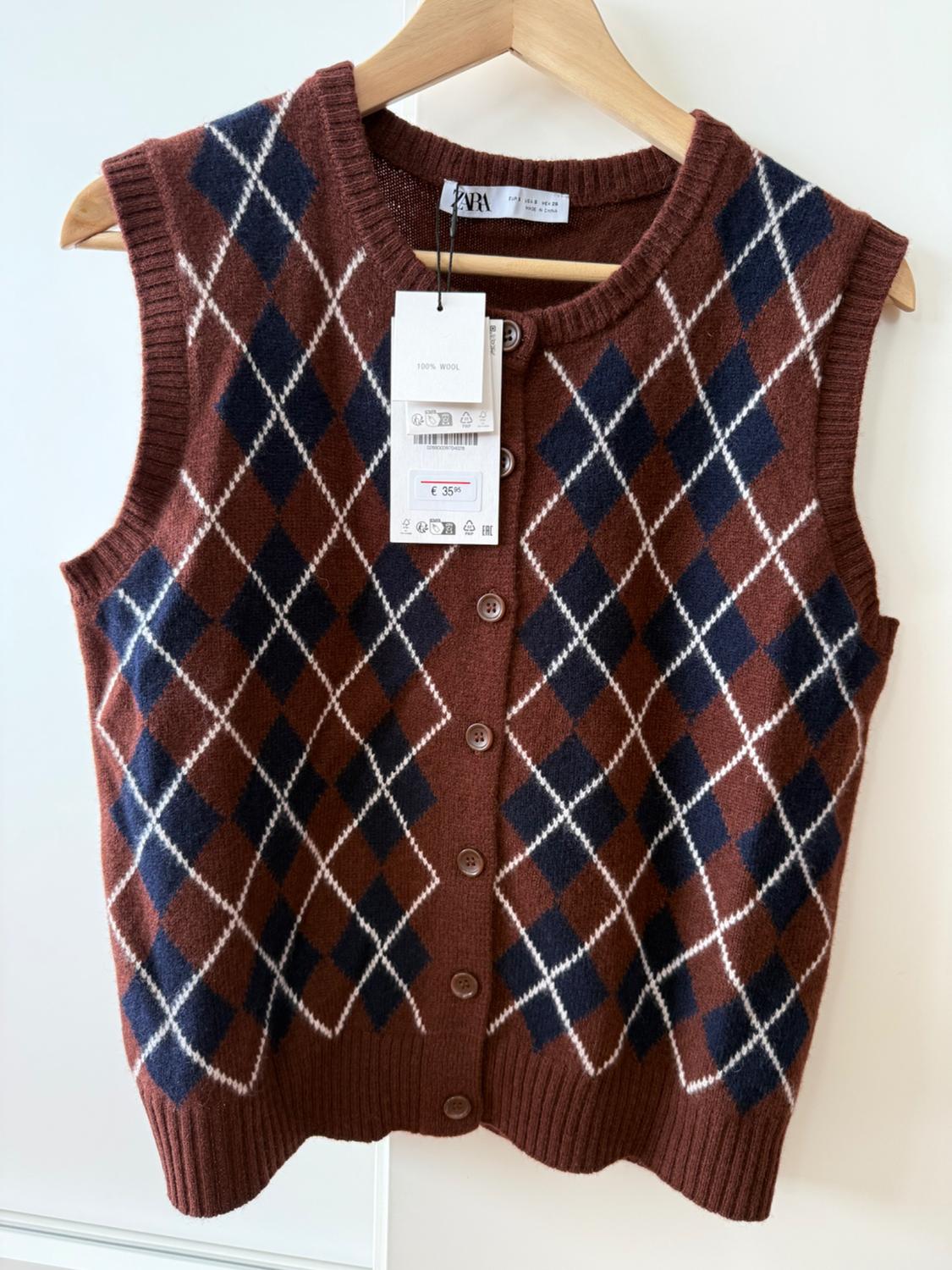 Brown wool waistcoat with blue and white argyle pattern, hanging on a coat hanger. Label shows price of £35.