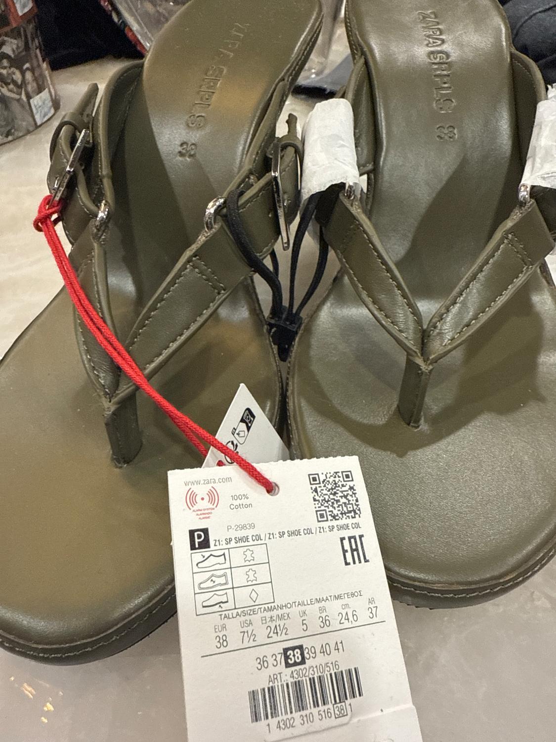 Close-up of olive green sandals with buckles and a visible size label.