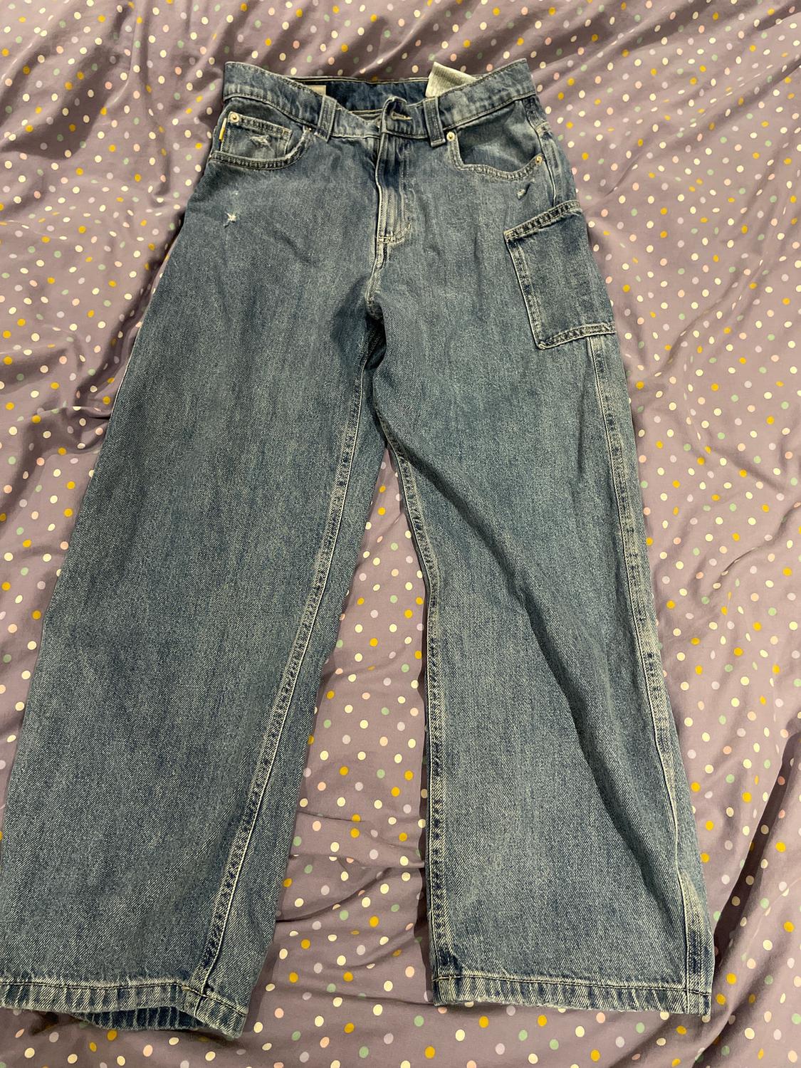 Blue, wide-leg jeans with pockets, on a purple quilt with white and yellow dots.