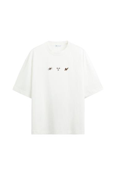 White t-shirt with three symbols printed on the chest: star, face, and butterfly. Visible label on the collar.