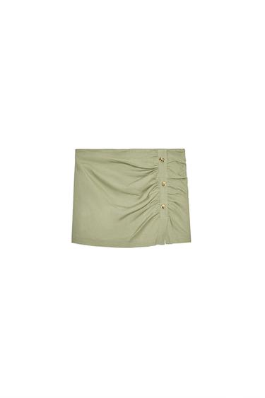 Front view of a short green skirt with side buttons and ruching.