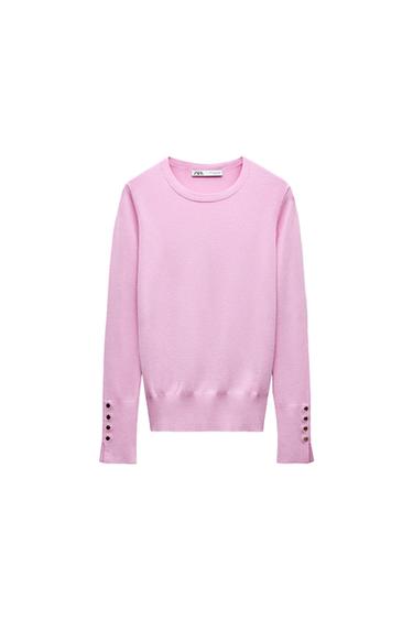 Front view of a pink jumper with button detailing on the cuffs.