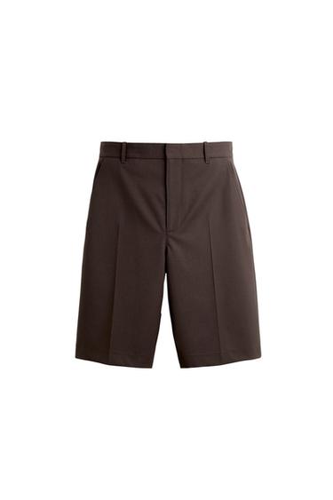 Brown tailored shorts with front pleats and belt loops, white background.