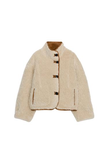 Front view of a reversible tan jacket with a high neck, long sleeves, front pockets and front button fastening.