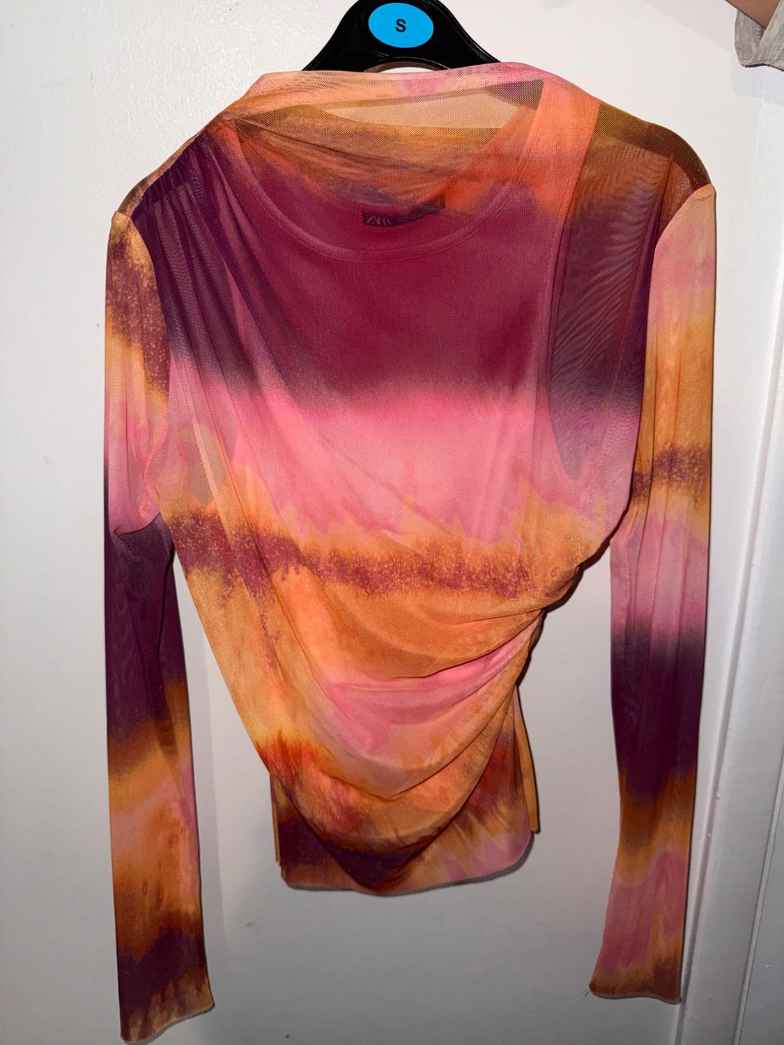 Semi-sheer ruched top with a pink, orange, and burgundy gradient. Hanging on a black hanger with an S sticker and a white ZARA label.