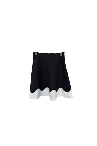 Front view of a black skirt with a white wavy hem.