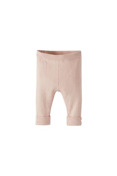 Front view of light pink trousers with a ribbed texture and turned-up cuffs.