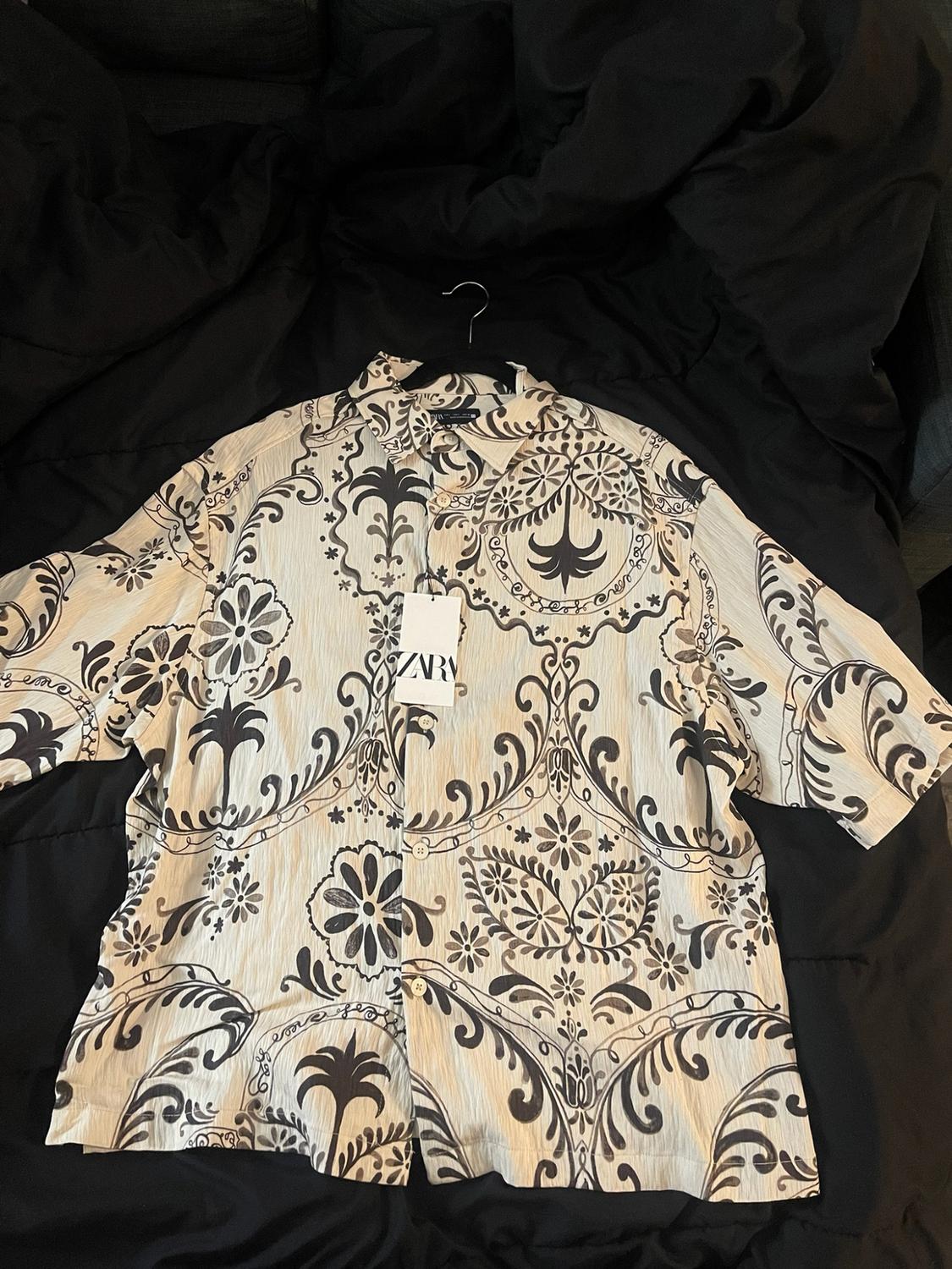 Light short-sleeve shirt with a dark palm and floral print on a black background. Label with the text ZARA.
