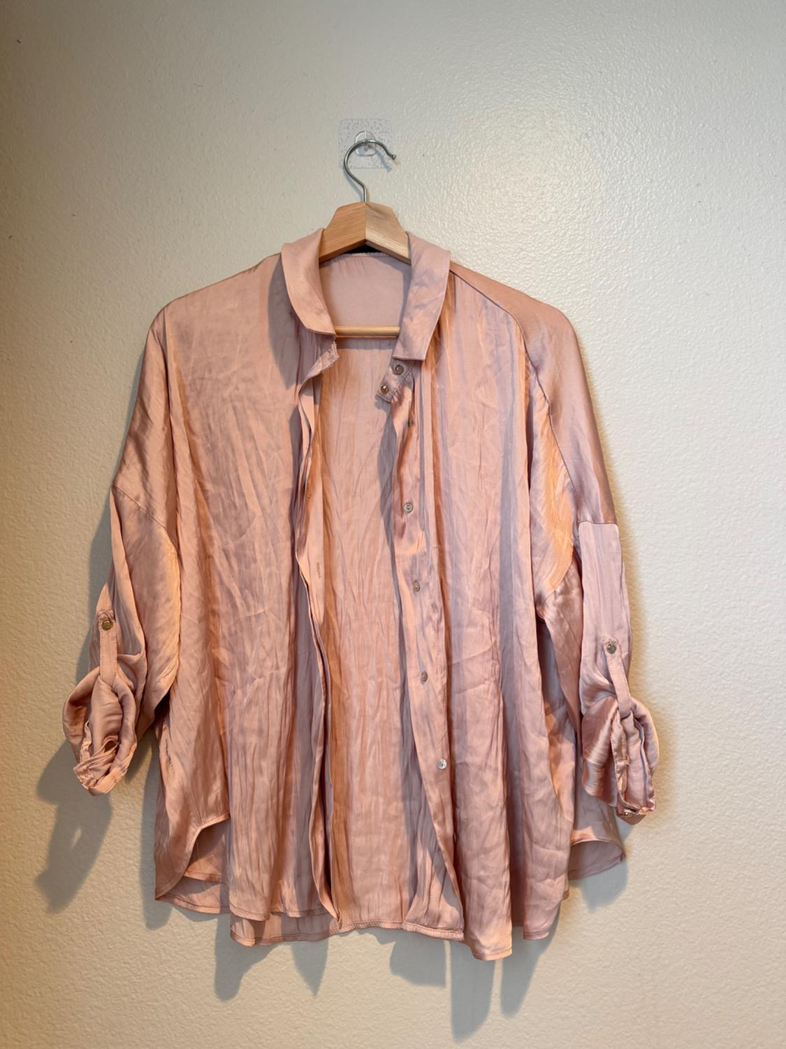 Front view of a pink blouse with buttons and rolled-up sleeves.