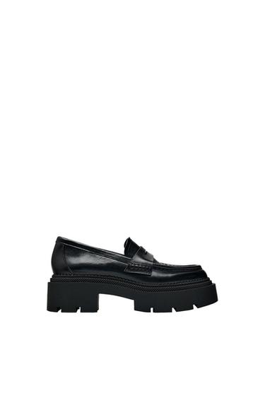 Side view of a black loafer with a thick sole and stitching details.