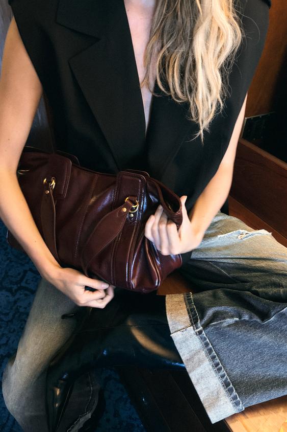 Bordo boja vlada sezonom i daje svakom outfitu luksuzan efekt 1 Plan srednje veličine crnog prsluka bez rukava s bordo torbicom i trapericama s crnim čizmama.