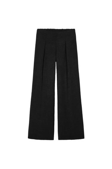 Front view of black trousers with pleats at the front.