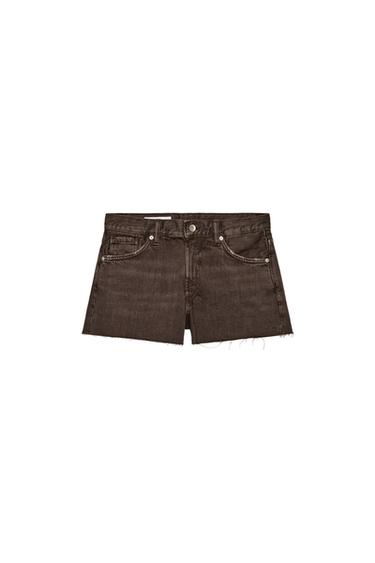Front view of brown Bermuda shorts with a mid-rise, five pockets, and a raw hem. Front zip fly and metal button closure.