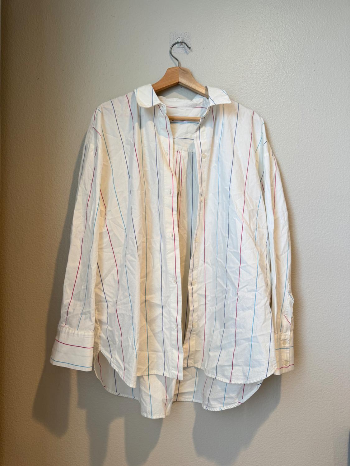 Front view of a white shirt with vertical red and blue stripes, classic collar and buttons.