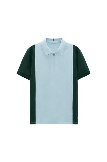 Short-sleeved polo shirt with zip, light blue and black. Visible inner label with "ZARA" text. White background.