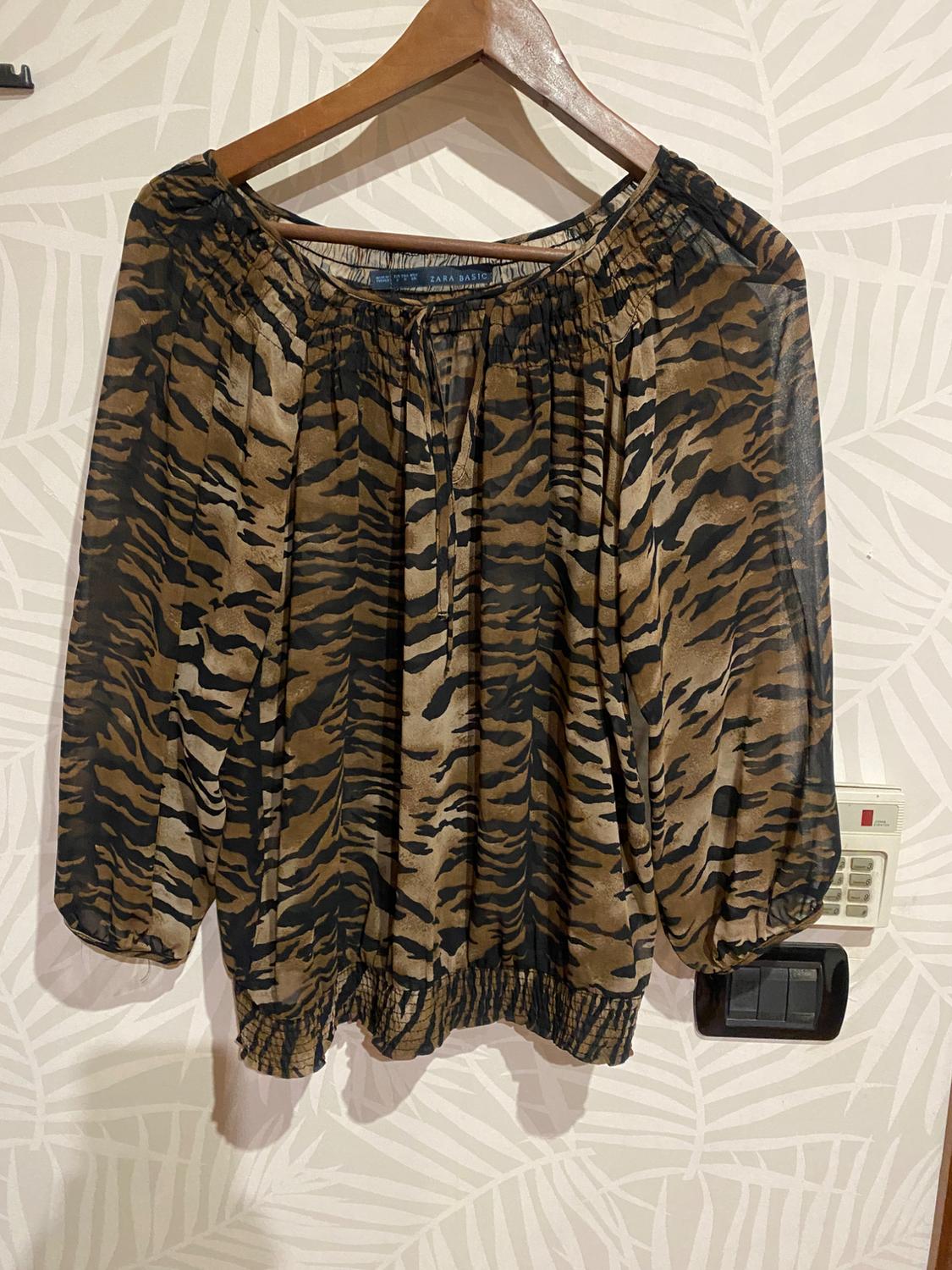 Front view of a printed blouse with a tiger pattern, long sleeves, and a shirred elasticated neckline.