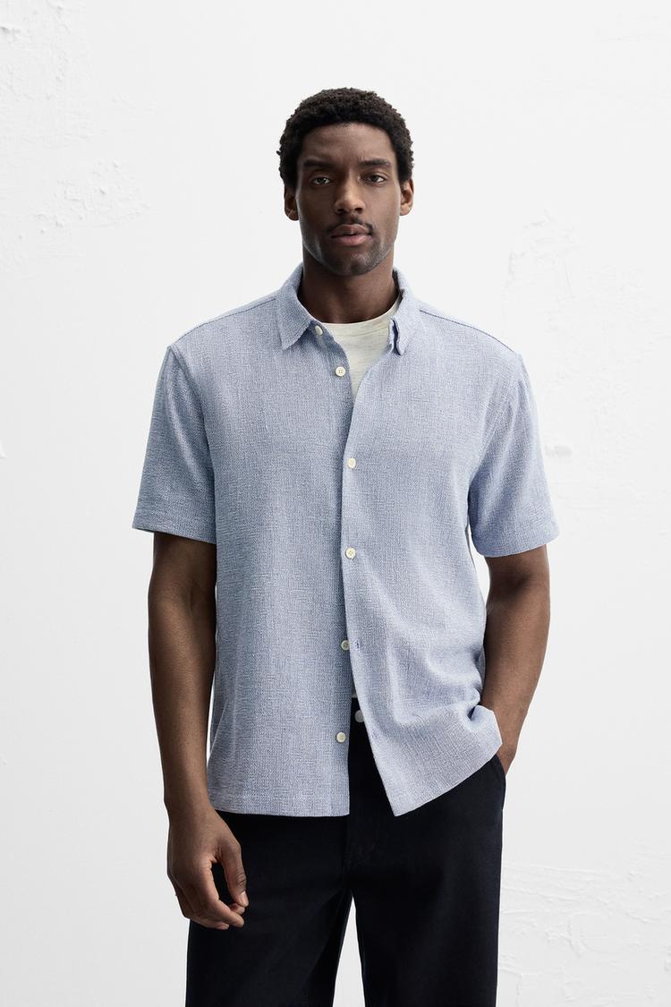 Relaxed fit shirt made of cotton blend fabric. Lapel collar and short sleeves. Side vents at hem. Front button closure.