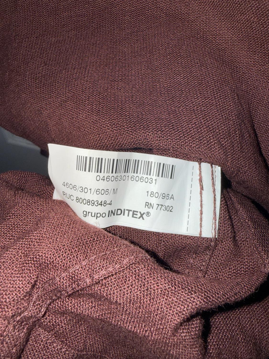 Close-up of a brown fabric label: 04606301606031 4606/301/606/M 180/96A RUC 80089348-4 RN 77302 INDITEX® group.