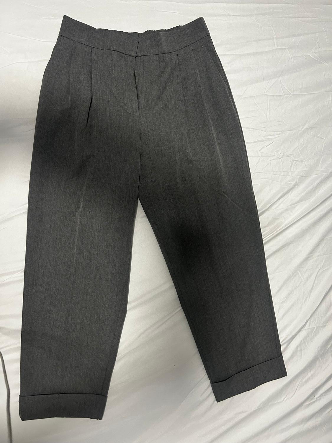 Dark gray lightweight fabric pants with pleats, elastic waist, and cuffed ankles, on a wrinkled white background.