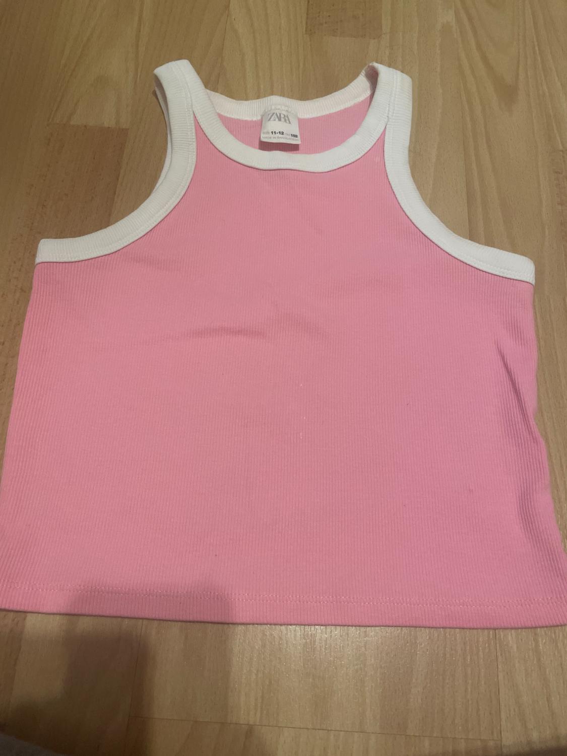 Pink sleeveless top with white trim on a wooden background. Visible label with text "ZARA 11-12 years".