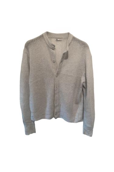 Light grey cardigan with front buttons and a round neck. Visible label inside the collar. White background.
