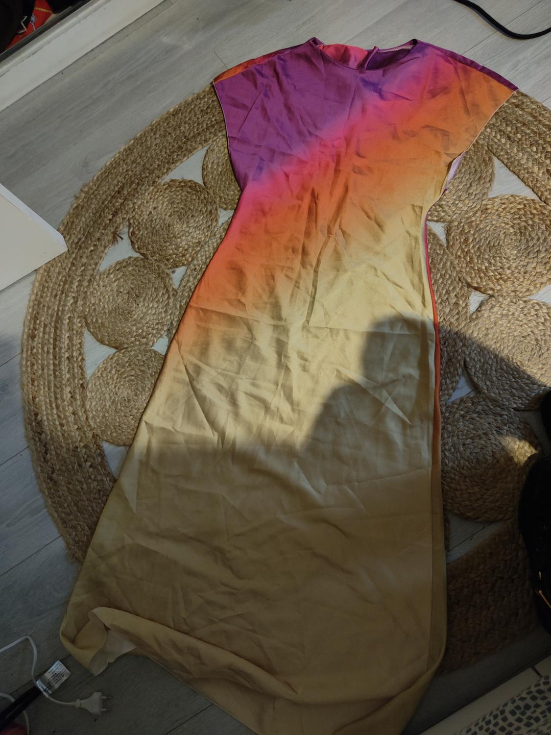 Long dress with purple, orange, and beige colour gradient on a jute rug on a light wooden floor.