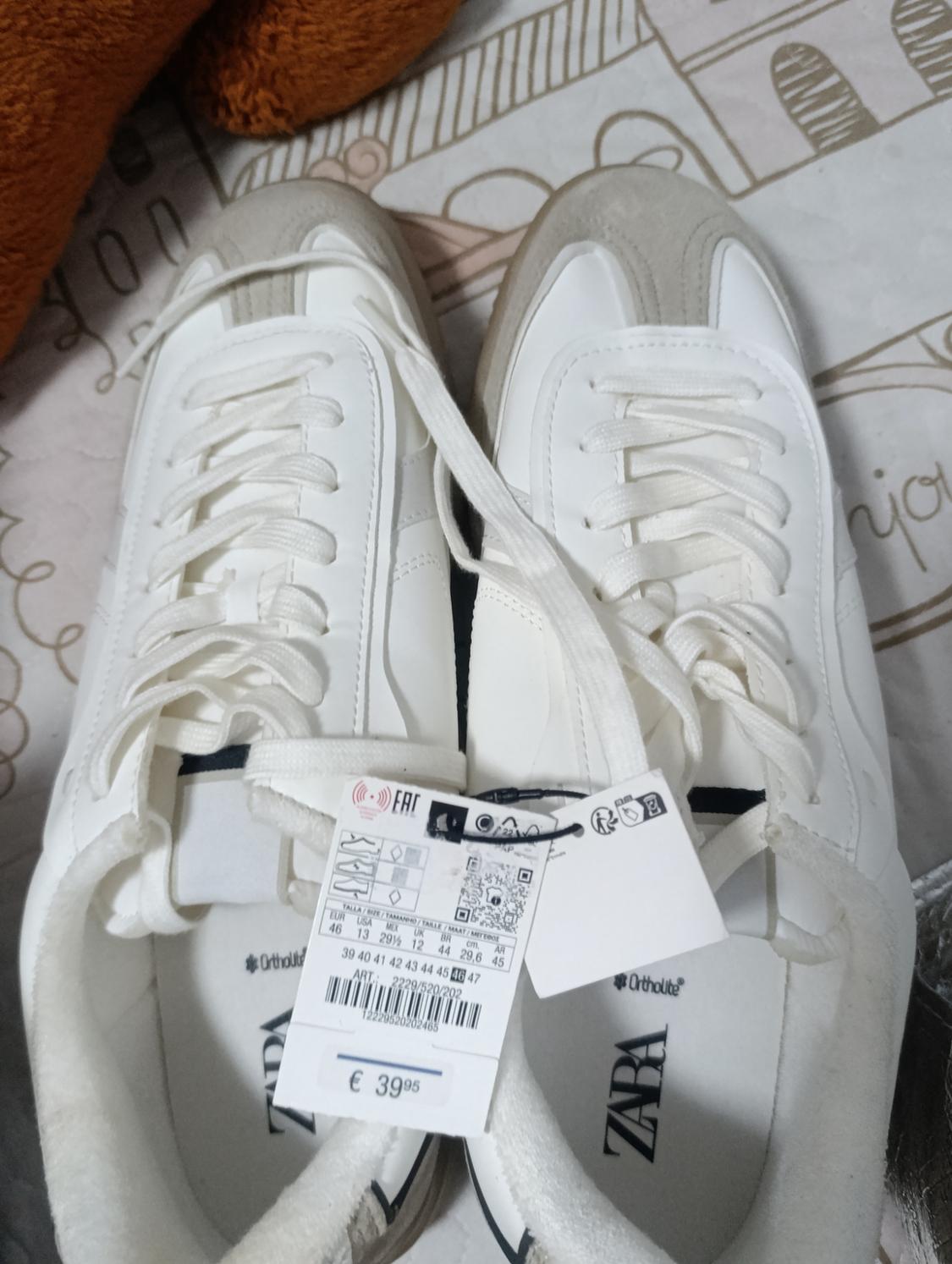White trainers with beige details and a price tag of €39.95. Background with a design of lines and geometric shapes.