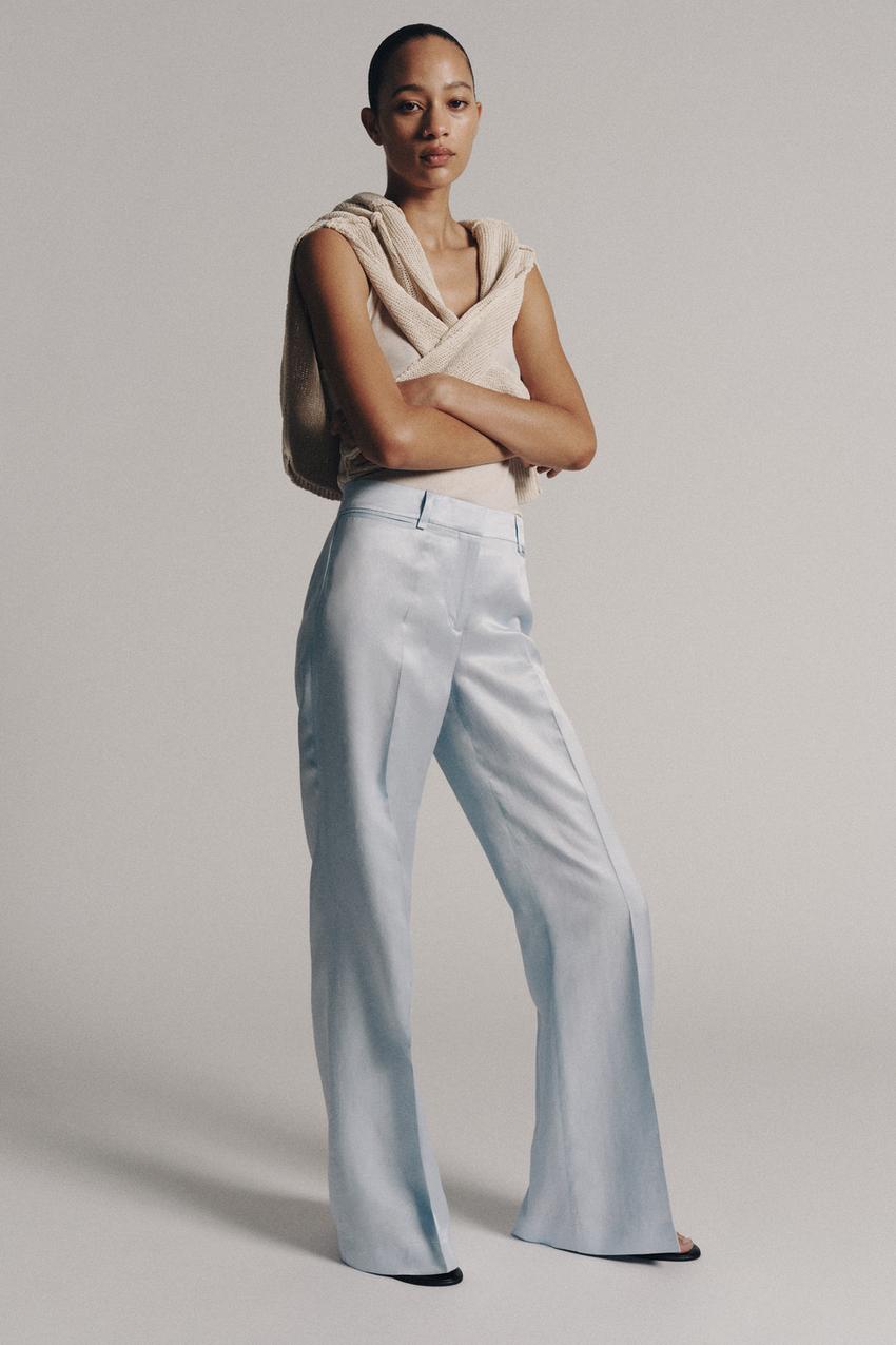 Beige top set, sweater tied at the shoulders, and light blue mid-rise, flared-cut long pants with belt loops and a front crease.