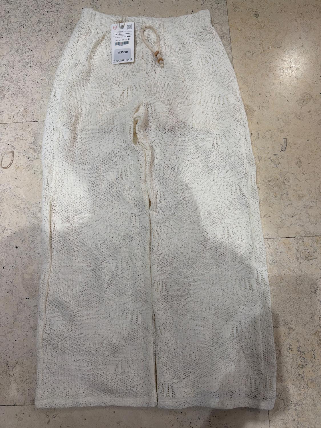 White wide-leg open-knit trousers with a drawstring on a tiled floor. Label with text: 13/14 164 $ 35.90.