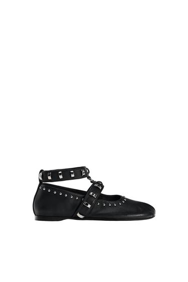 Flat black shoe with ankle strap, instep strap, buckles and silver studs on a white background.