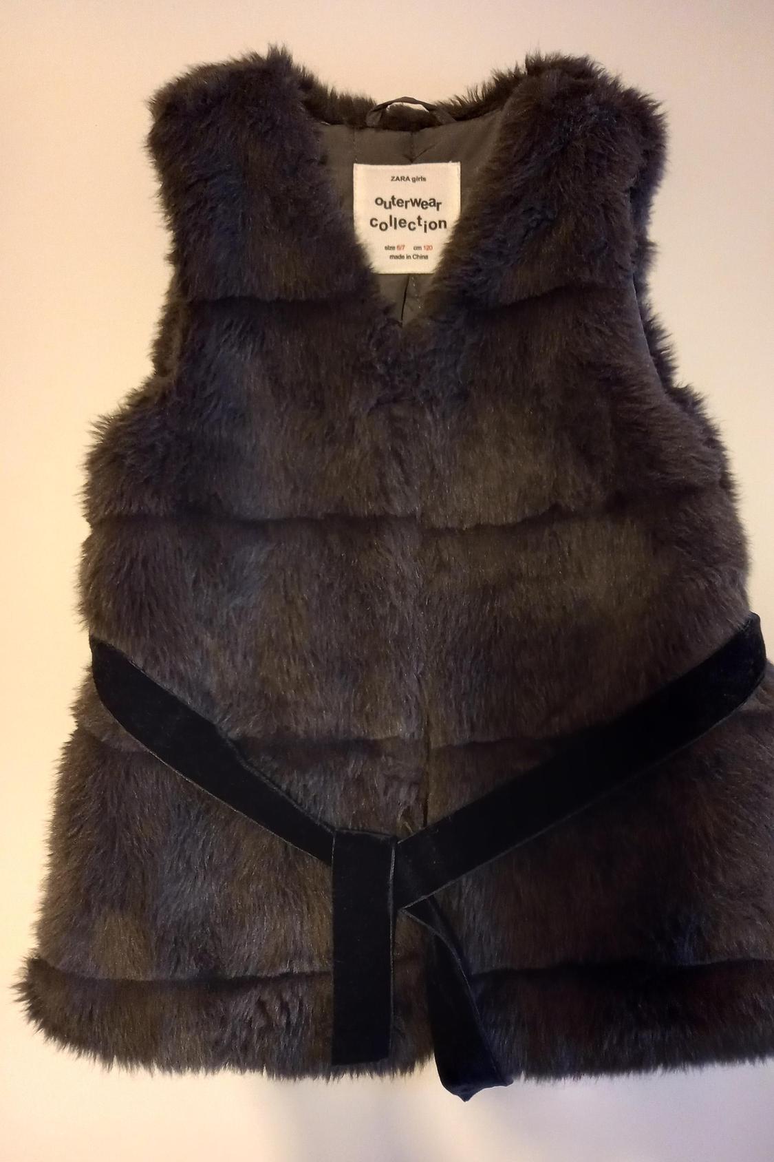 Front view of fleecy grey gilet with black belt and 'ZARA girls OuterWear Collection' label.
