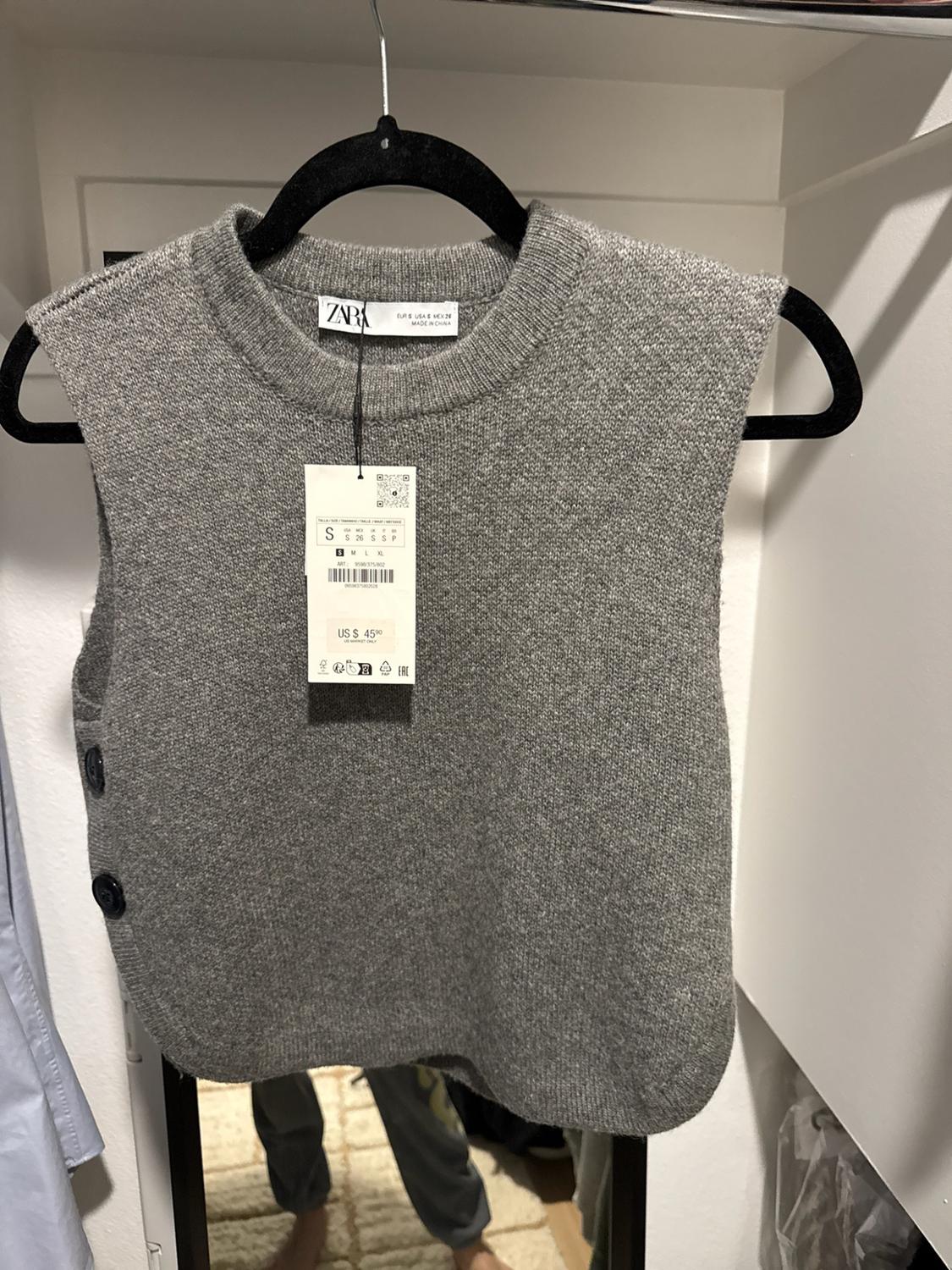 Gray knit vest hanging on a hanger. Visible text: ZARA, EUR S USA S MEX 26, MADE IN CHINA, S, US $ 45.90.