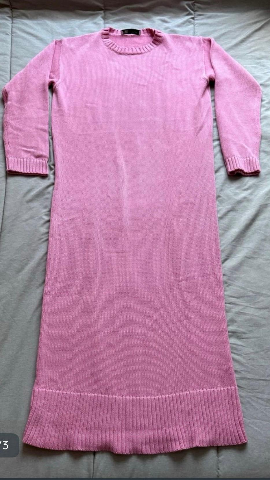 Pink long-sleeved knitted maxi dress with a round neck, laid flat on a grey surface.