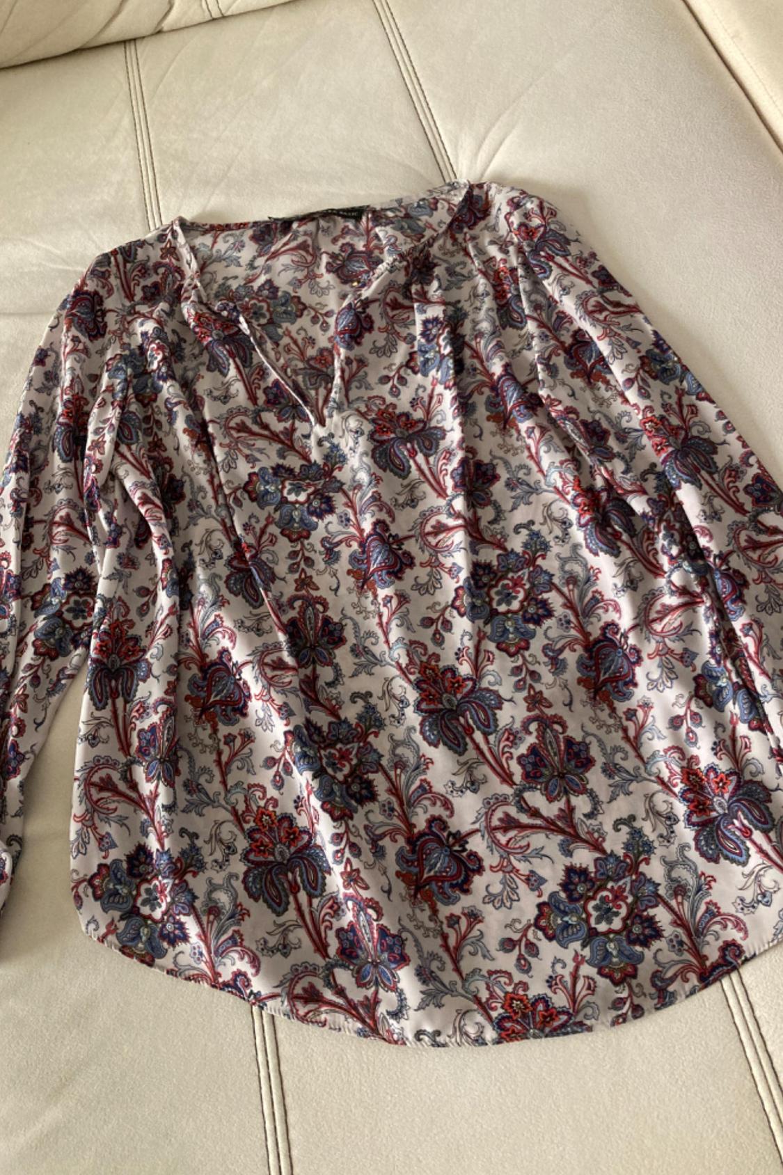 Front view of a printed blouse with red and blue floral tones, a V-neck and long sleeves.