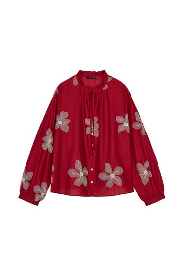 Front view of a red blouse with a white floral print, tie neck and front buttons.