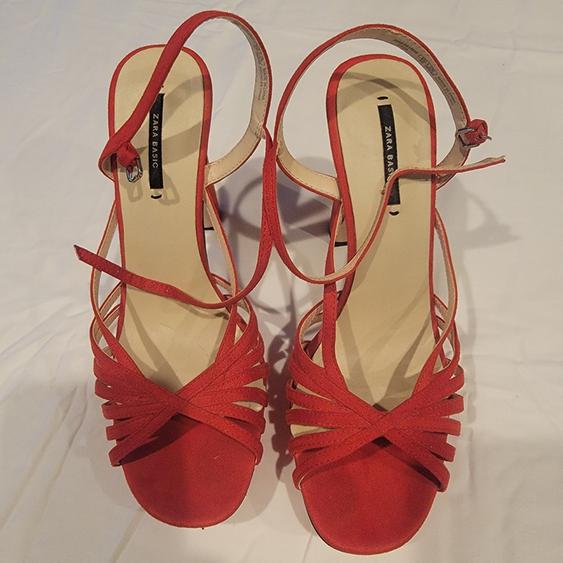 Red cross-strap sandals with heels and buckle closure, on a white background. Visible text: "ZARA BASIC".